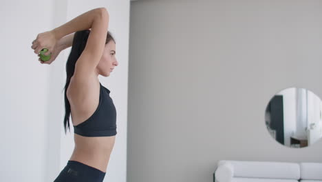 A-young-girl-raises-her-arms-with-dumbbells-from-behind-her-head-doing-triceps-exercises.-Triceps-training.